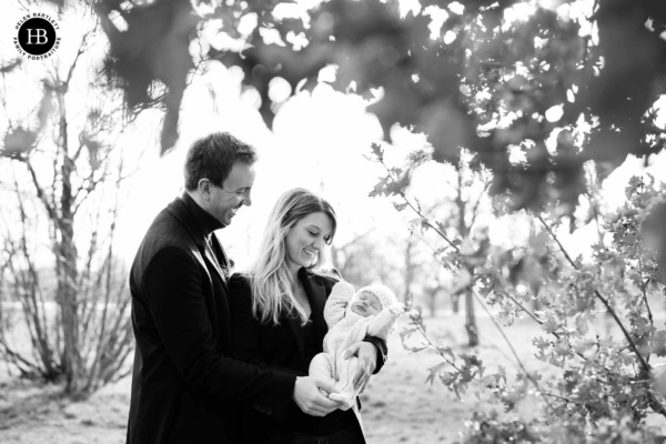 parents hold newborn baby in winter day at the park, professional newborn baby photograph