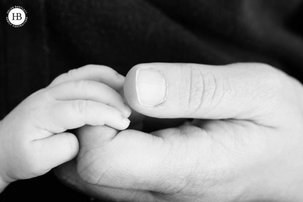 detail shot of dad holding newborn baby son's hand