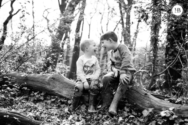 Boys laugh together as they sit on a log in Streatham Woods