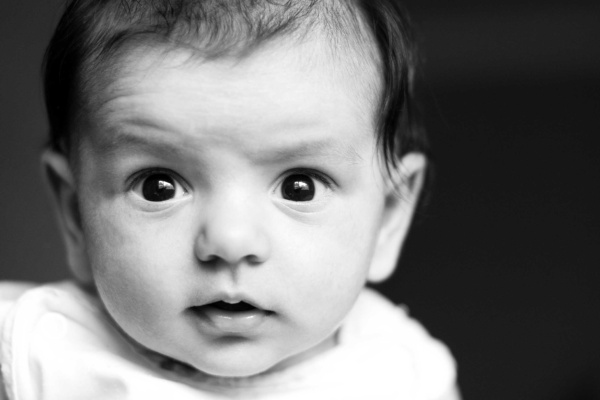 Newborn baby held close by a parent during a natural black and white photography session at home