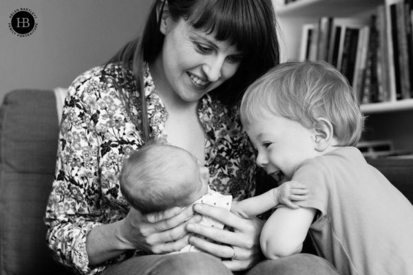 Older sibling meeting their newborn brother or sister at home, photographed in a natural documentary style