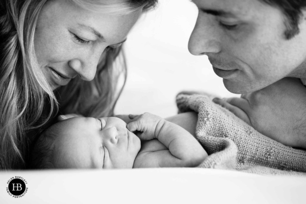 Parents cradling their newborn at home during a natural lifestyle photography session