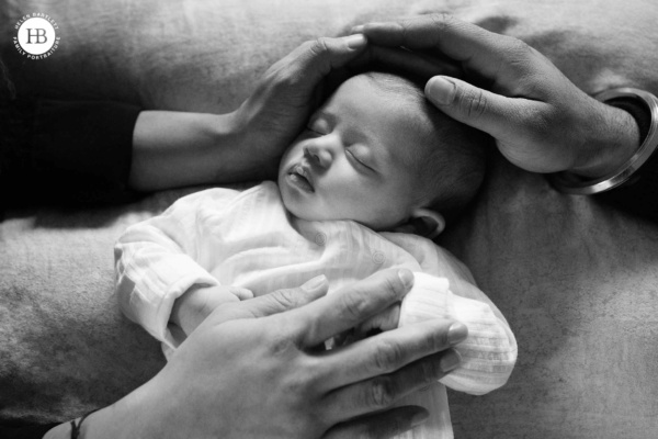 sleeping newborn comforted by parents hands