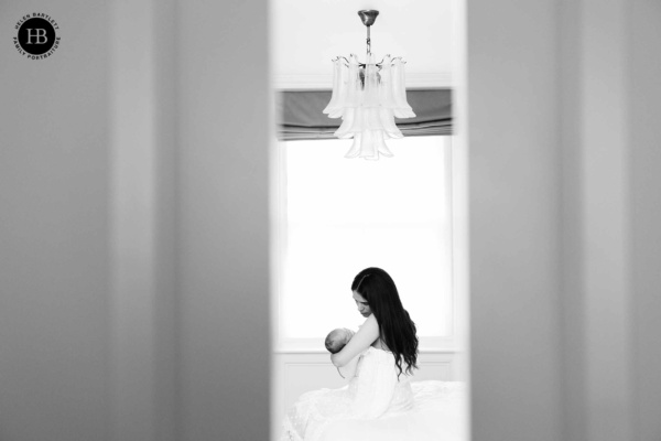newborn and mother sit on bed during professional newborn photography session in primrose hill