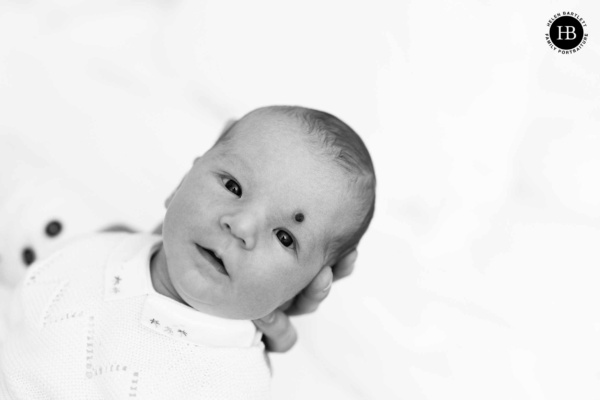 portrait of newborn baby looking at camera while held by parent