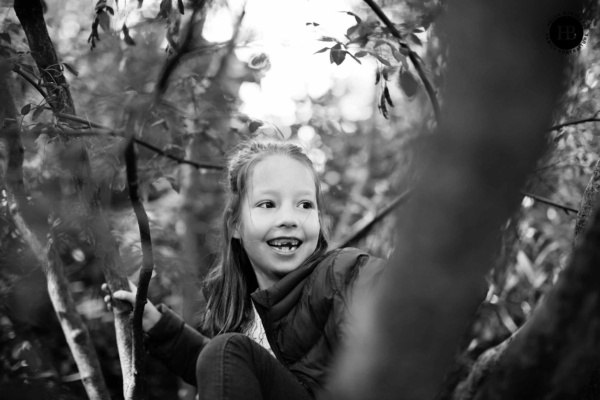 Girl sits in a tree laughing. A shallow depth of field adds to a creative composition.