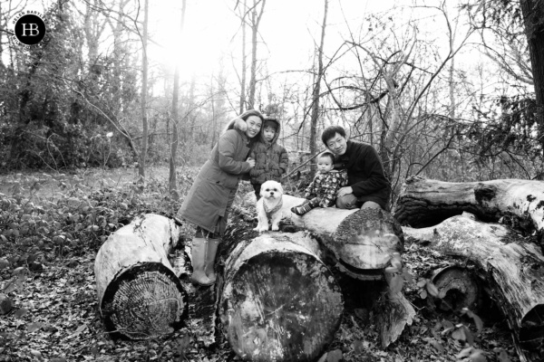 A frosty morning is perfect for this family photo where parents, two children and a dog sit on logs on Wimbledon common.