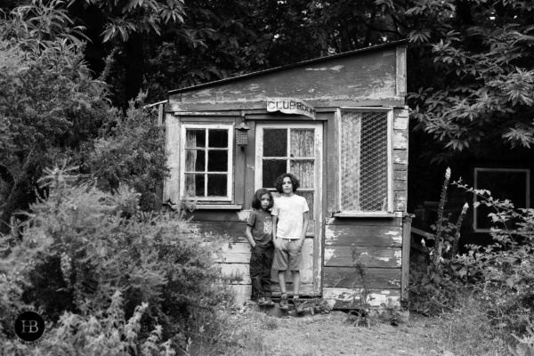 boys stand in front of shed with clubhouse sign falling off
