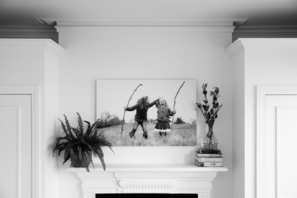 An acrylic family wall portrait over a fireplace in a minimalist home with white walls.