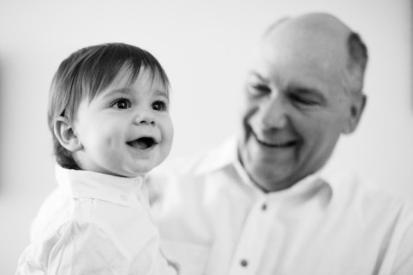 A baby and his family pose for a black and white portrait.