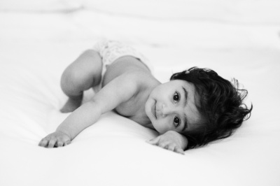 A baby crawls across a bed, towards the photographer.