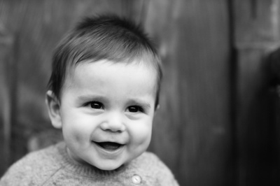 A baby grins in a black and white portrait.