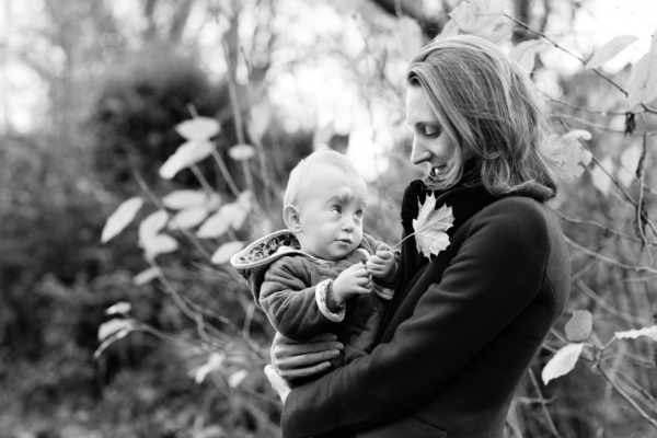 A baby holds a leaf in their mother's arms.