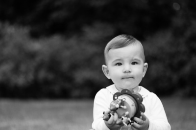 Baby holds toy against a dark background.