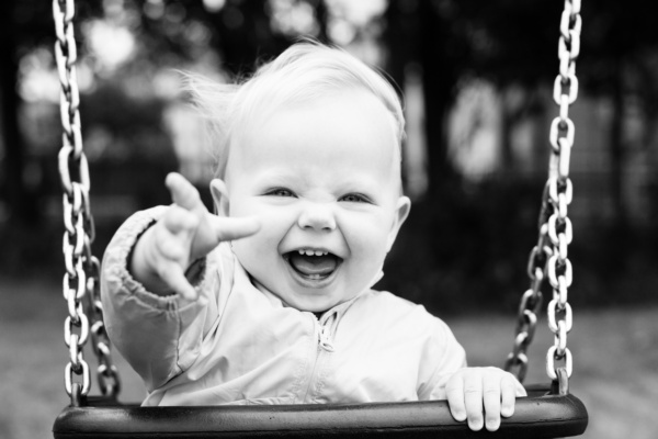 A baby in a swing reaches out.