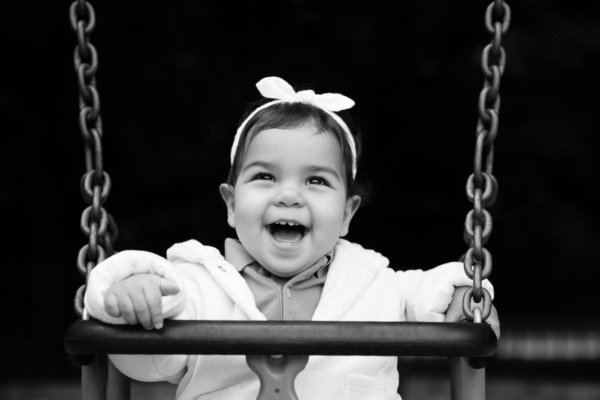 A baby in a swing smiles.