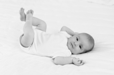 Baby kicks their feet on their family bed.