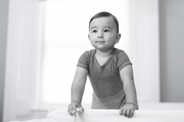 Baby leans on the edge of his cot.