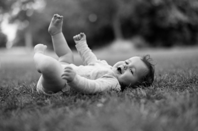 A baby lies on thick grass.