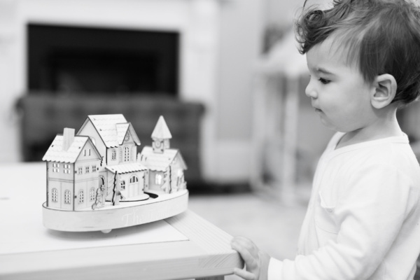 Baby looks at a toy house while in their family home.