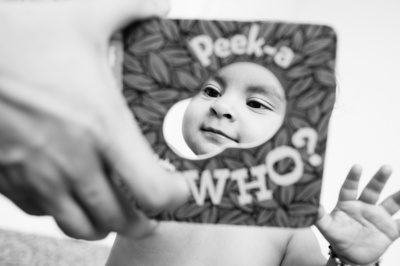 A baby peeks through a book window.