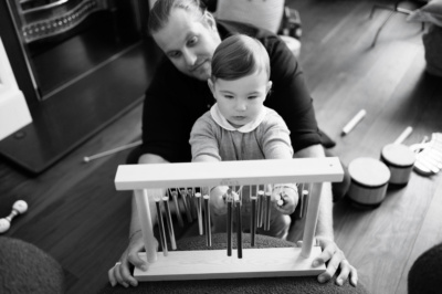 A baby plays music with his father in their home.