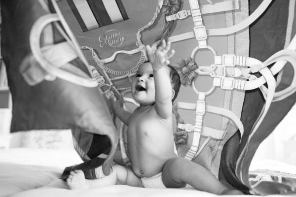 A baby reaches into the air during a black and white portrait shoot.