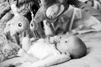 A baby sees their own reflection in suspended toys.