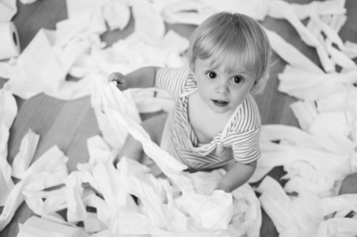 A baby shreds toilet rolls.