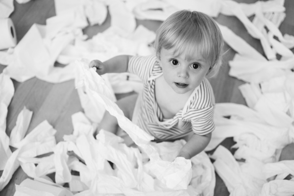 A baby shreds toilet rolls.