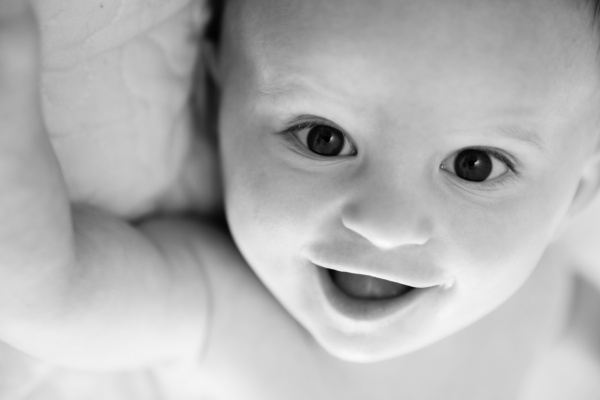 A baby smiles at London baby photographer Helen Bartlett during a portrait shoot.