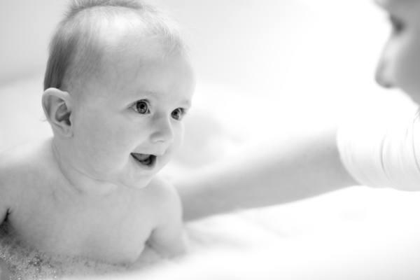 Baby smiles in bubble bath.