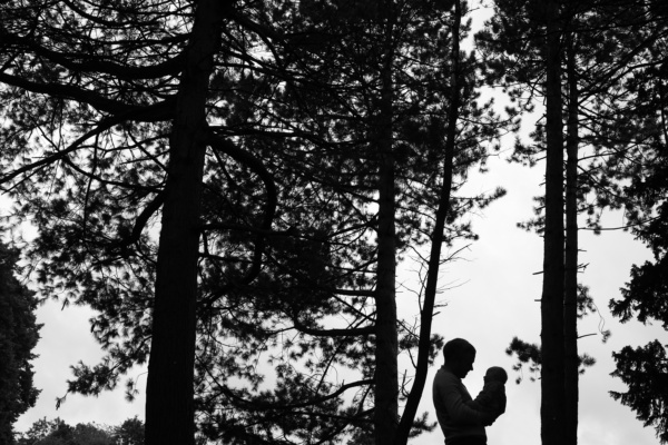 A father and baby silhouette between trees.