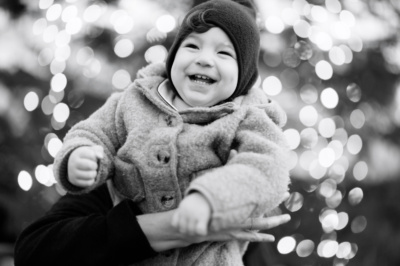 A baby giggles in front of Christmas lights in Covent Garden.