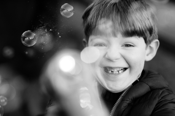 Boy blows bubbles outdoors.