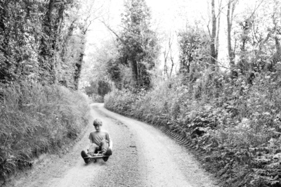 Boy carts down country lane.