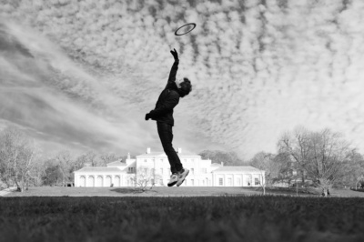 A boy catches a frisbee near Kenwood House.