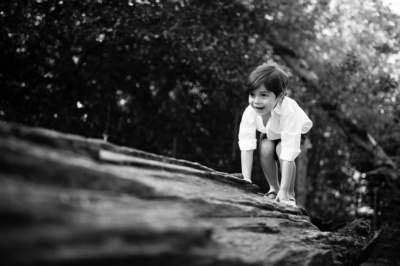 A boy crawls along a log.