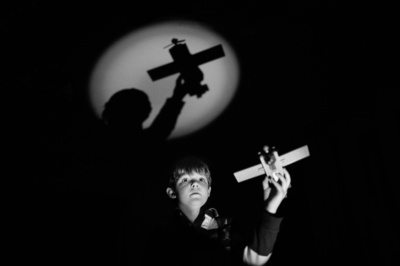 A boy flies a toy plane, with a shadow reflected on the wall.