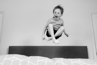 A boy jumps on a bed.