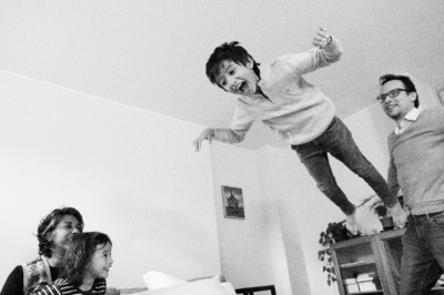 A boy jumps while his family watches.