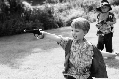 Boy plays cowboys in the garden.