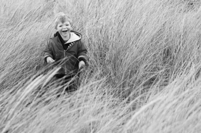 A boy plays in the grass on a sand dune.