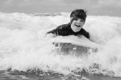 A boy rides waves on his boogie board.