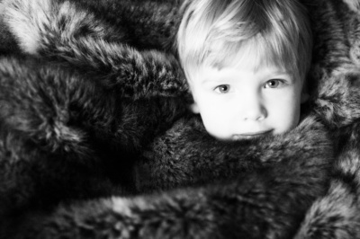 Boy snuggles in fur blanket.