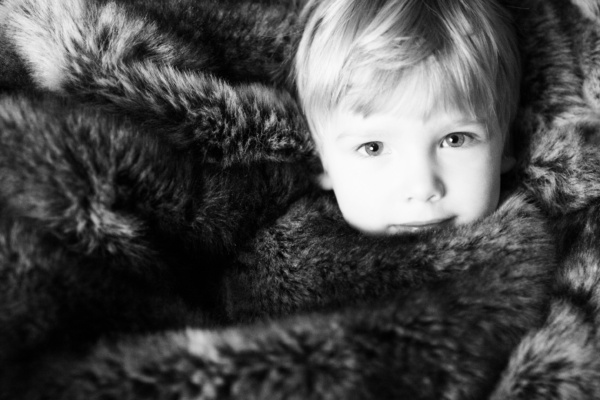 Boy snuggles in fur blanket.