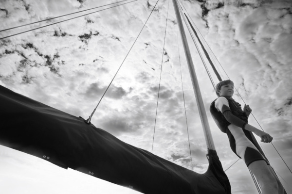 A boy stands on a boat bow.