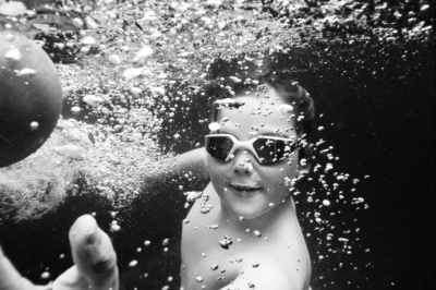 Boy swims underwater, surrounded by bubbles.