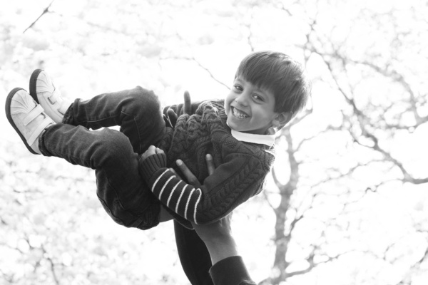 A father swings his son into the air during a London vacation.