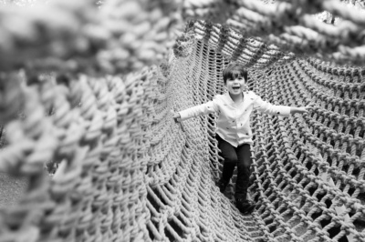 A boy walks across a rope bridge.